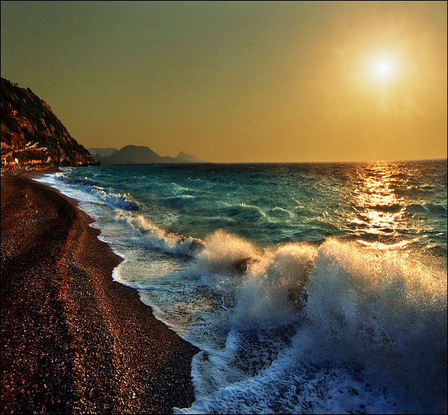 "photograph of the ocean meeting the shore at sunset"