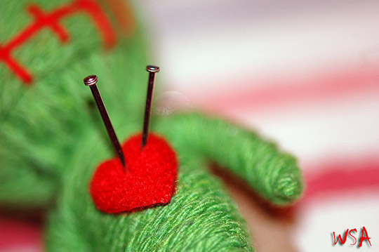 "photo of voodoo doll with needles in heart"